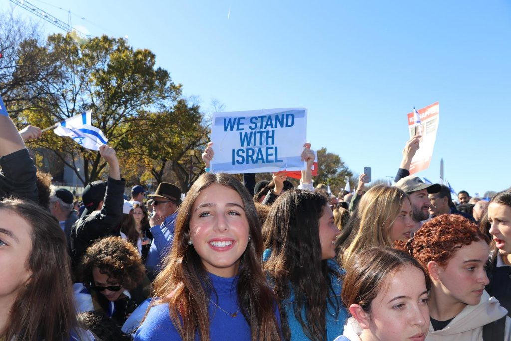 Group of people holding 'We Stand with Israel' signs at a peaceful gathering.